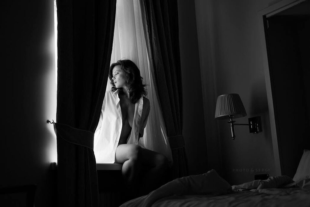 Naine istub hotellitoa aknalaual, mustvalge foto