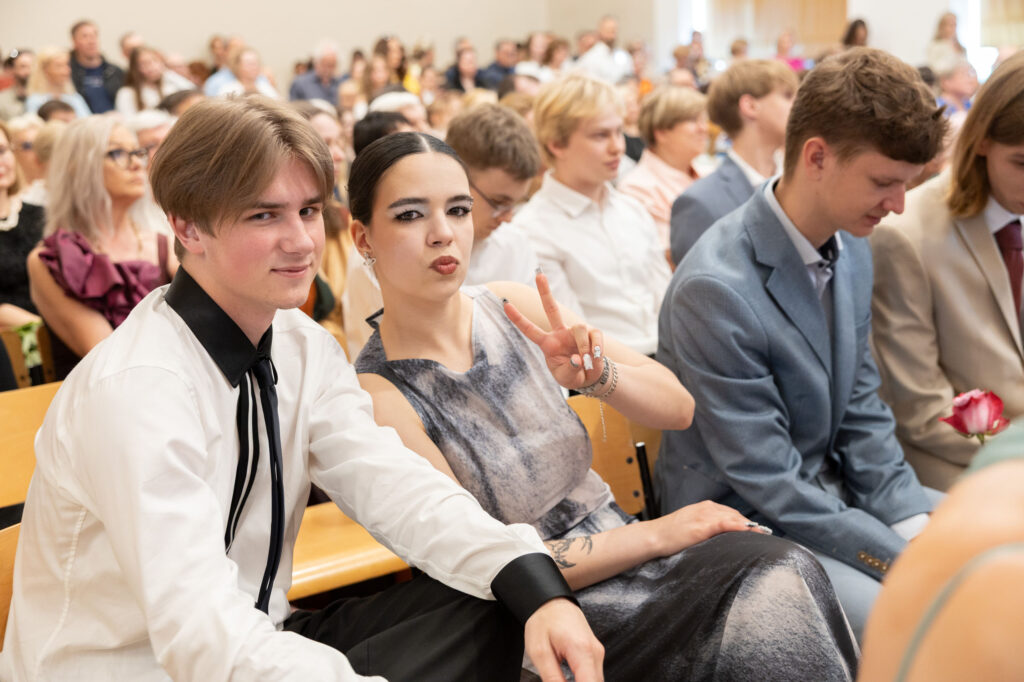 Lõpetajad aktusesaalis, tüdruk näitab V-märki